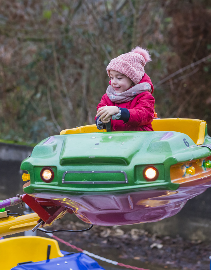 Meisje zit in een kermisattractie in het Sprookjesbos met muts